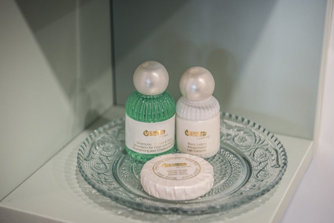 A bathroom shelf with two bottles of Touch Classic shampoo and body lotion, and a bar of soap.