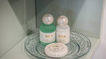 A bathroom shelf with two bottles of Touch Classic shampoo and body lotion, and a bar of soap.