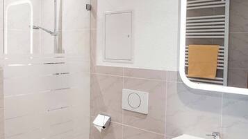 A bathroom with a glass-enclosed shower, a white toilet, a sink, and a towel rack.