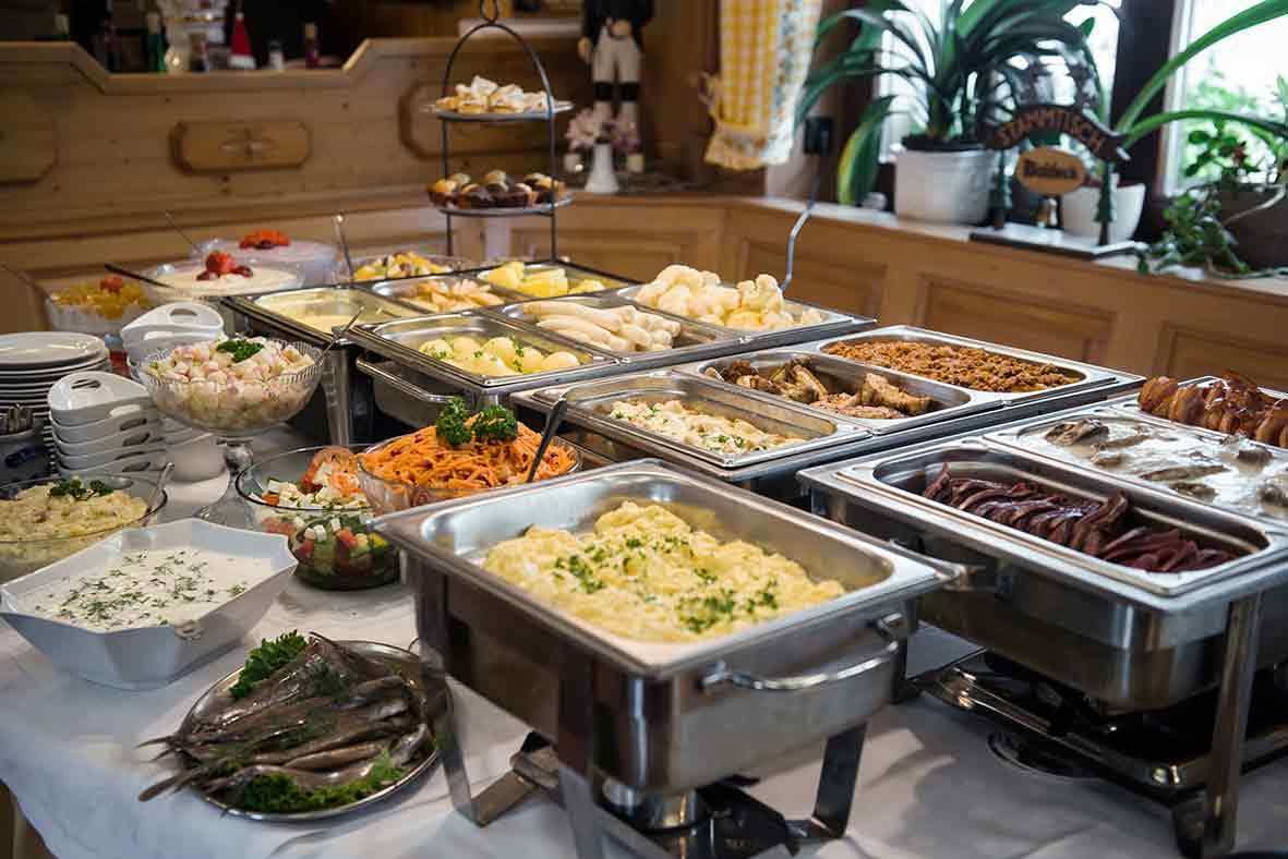 Un bufé con diversas opciones de comida, incluyendo ensaladas, carnes y postres.