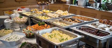 Un bufé con diversas opciones de comida, incluyendo ensaladas, carnes y postres.