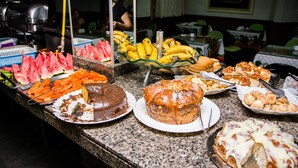 Un bufé con diversas opciones de comida, incluyendo sandía, plátanos y una variedad de postres.
