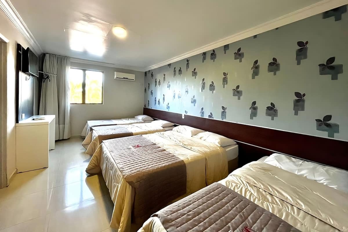 A hotel room with two beds, a desk, and a window with curtains.