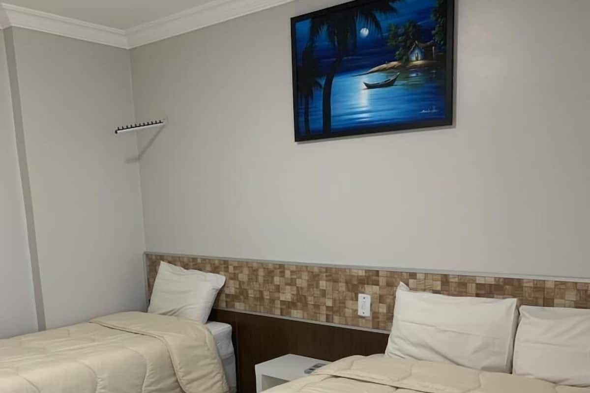 A hotel room with two beds, a night sky painting, and a tiled wall.
