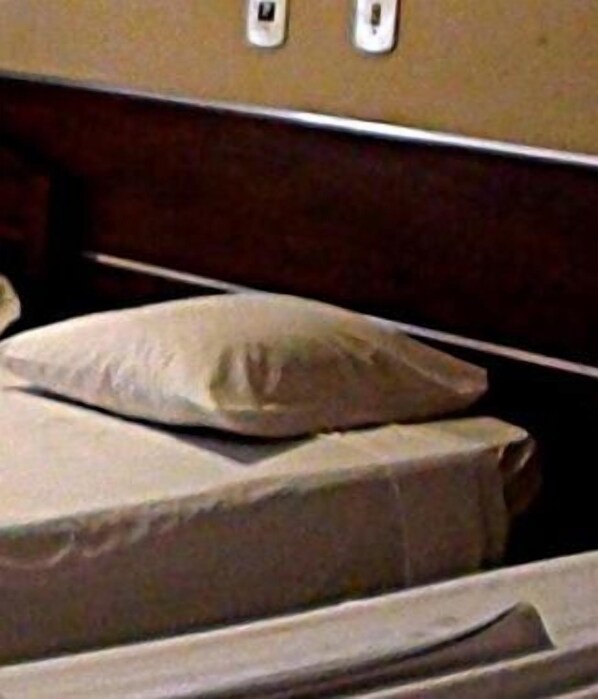 A bed with a mattress and pillows in a room with a wooden headboard.