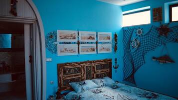 Un dormitorio con una pared azul, una cama de madera con temática náutica y una ventana con vistas.