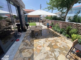 A patio with a stone floor, outdoor furniture, and a large umbrella.