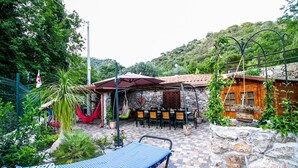 Eine Terrasse mit einer Hängematte, Gartenmöbeln und einer Steinmauer.