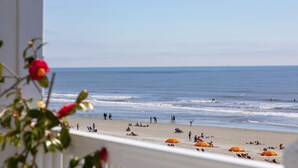 A beach with people, umbrellas, and a clear sky.