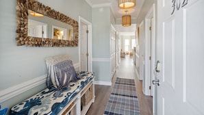A hallway with a bench, a mirror, and a door labeled "302".