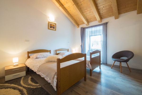 A bedroom with a wooden bed, a nightstand, a chair, and a window with curtains. - Fully fenced, pet-friendly, ideal for families (Žminj)