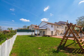 A house with a patio, a pool, and a wooden play structure.