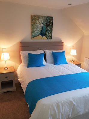 Relax in a serene space with a large bed, two nightstands, and a beautiful peacock artwork above.