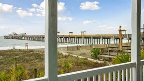 A wooden pier extending into the water with a series of small structures along its length. - Luxury Oceanfront with porch and swing daybed! Pet Friendly w/ fee, Elevator - Seaside Villa 101 (Folly Beach)