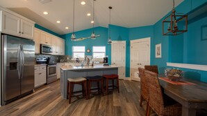 A modern kitchen with a central island, stainless steel appliances, and a teal accent wall. - Beach front home perfect for a family or couple.  Amazing view. (Port St Joe)