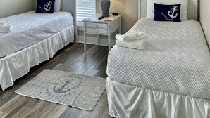 A room with two beds, a ceiling fan, a window with blinds, a lamp, and a wall decoration. - Beach front home perfect for a family or couple.  Amazing view. (Port St Joe)