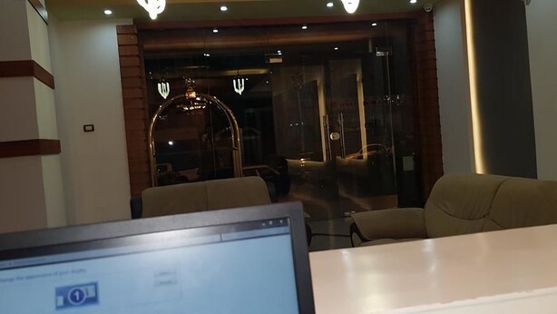En moderne hotellobby med reception, siddeområde og en glasindgang.