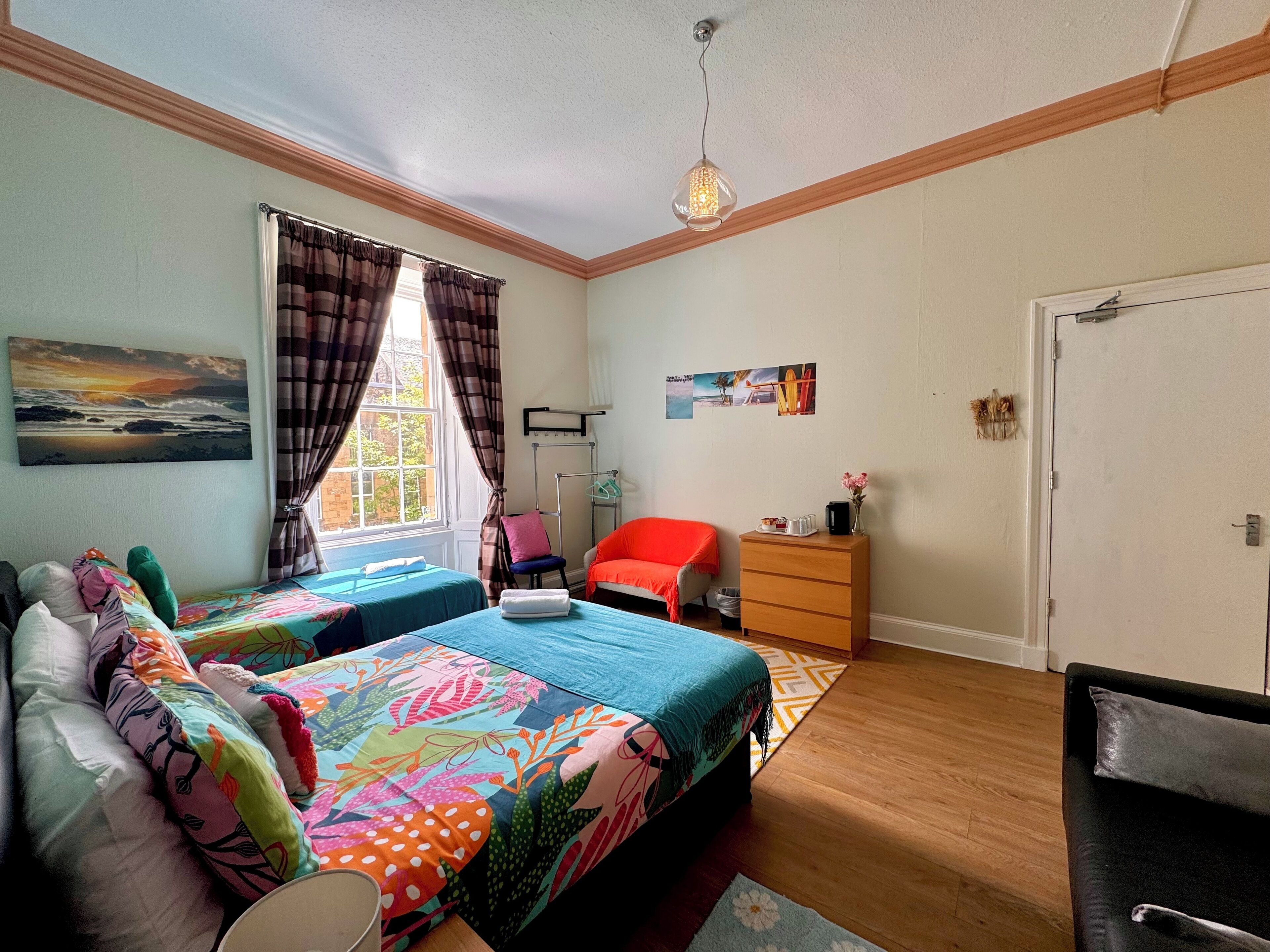 A bedroom with two beds, a chair, a dresser, and a door.