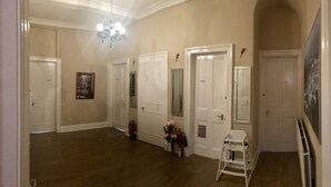 A hallway with four white doors, a white chair, and a fire extinguisher. - @part Bernard Rooms (Edinburgh)