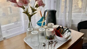 A table with a vase of flowers, a kettle, a mug, and a tray with utensils. - @part Bernard Rooms (Edinburgh)