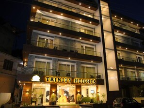 A multi-story hotel named Trinity Heights with balconies, large windows, and a well-lit entrance.