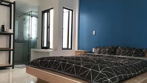 A modern bedroom with a bed, a walk-in closet, and a shower area. - The Land of Canaan (Da Nang)