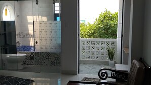 A modern bathroom with a toilet, sink, and shower area. There is a balcony with a white lattice fence and a potted plant. - The Land of Canaan (Da Nang)