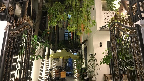 An indoor garden with hanging plants and a sign reading "Homestay & Coffee The land of Caan". - The Land of Canaan (Da Nang)