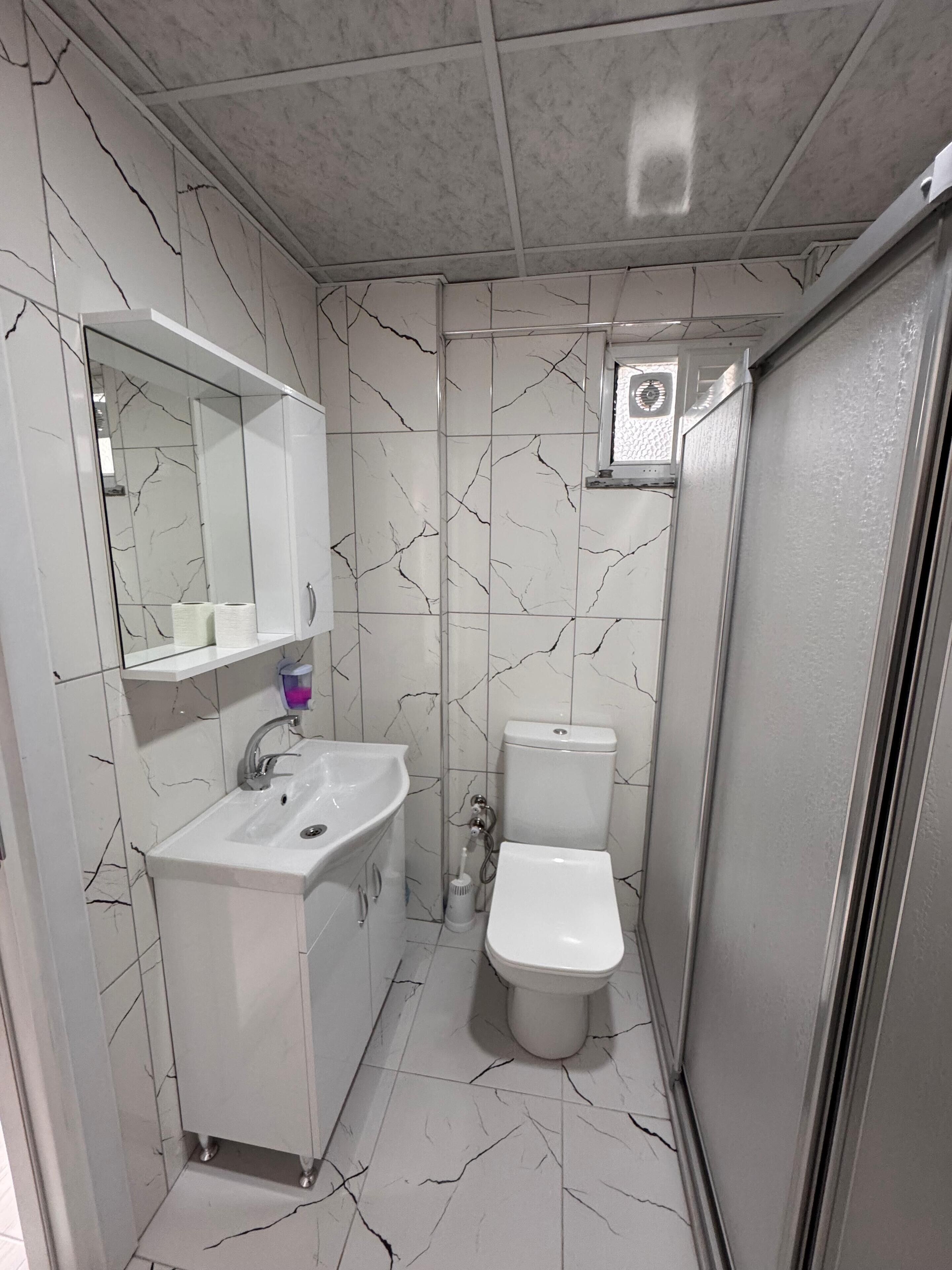 A compact bathroom with a white sink, mirror, and toilet.
