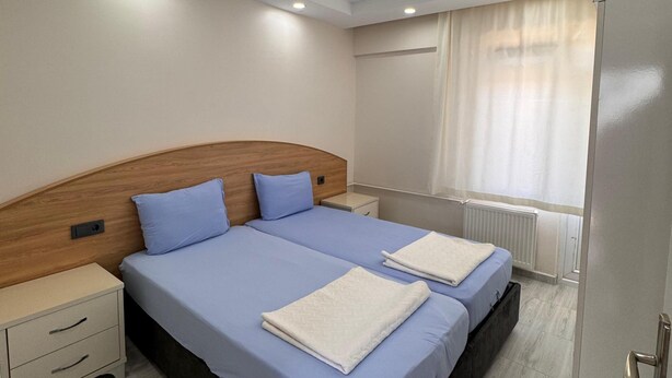 Una cama doble con cabecera de madera, una mesita de noche y una mesita auxiliar.