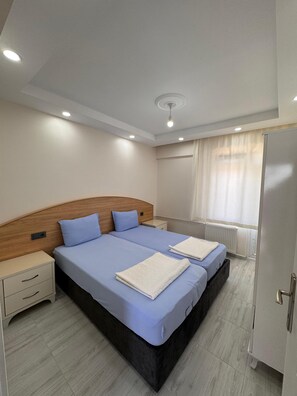 A double bed with a wooden headboard, a bedside table, and a nightstand.