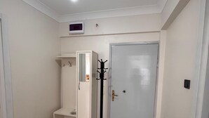 Una habitación con un armario blanco, perchero, puerta y una lámpara en el techo.