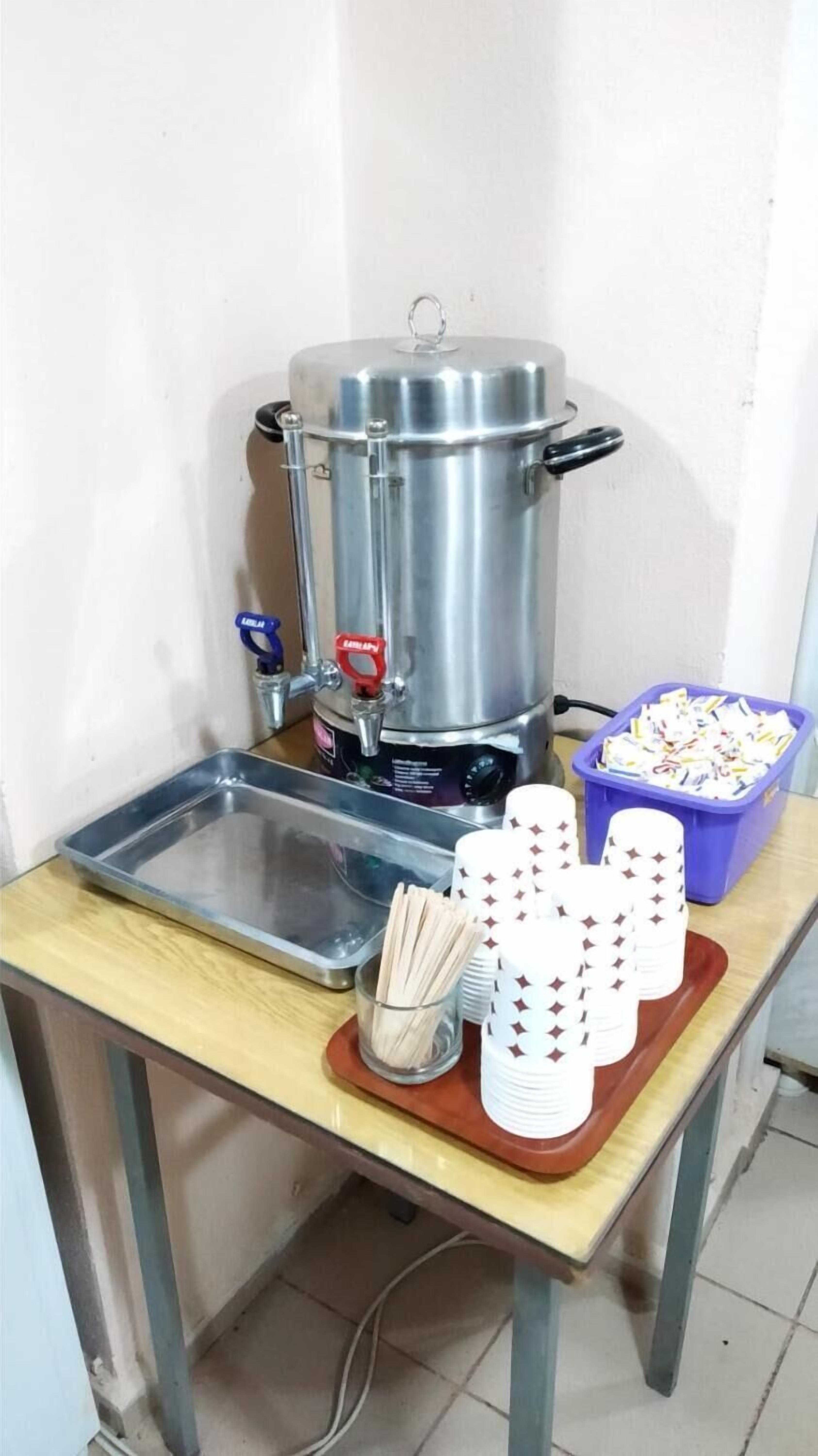 A coffee station with a coffee machine, a tray, and disposable cups.