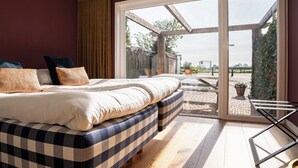 Un dormitorio con una cama grande, vistas al exterior a través de un ventanal corredero y suelo de madera.