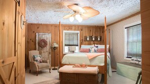A cozy bedroom with a four-poster bed, a wooden wardrobe, a chair, and a bedside table. -  Cottage in the Woods- "Hummingbird"-- 2mi from Ricketts Glen falls trailhead! (Sweet Valley)