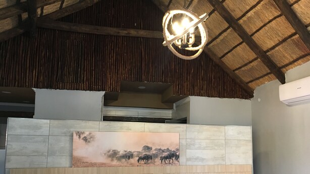 A bedroom with a wooden headboard, a large painting, and a unique circular light fixture.