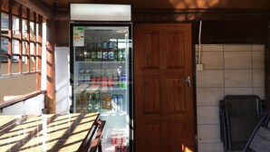 A vending machine stocked with beverages, a wooden door, and a tiled wall.