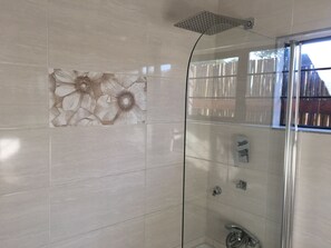 A shower with a glass door, a showerhead, and a wall-mounted control panel. - Thomo's Inn (Maun)