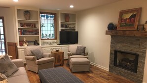 A living room with a fireplace, two armchairs, a sofa, a coffee table, and a bookshelf. - Natchez Trace Cabin Retreat on 5 acres (Canton)