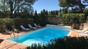 A rectangular swimming pool with a clear blue water surface, surrounded by a stone wall and a row of white lounge chairs. - Architect's Villa In The Heart Of The Vines Near Avignon (Châteauneuf-de-Gadagne)