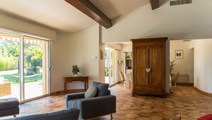 A spacious living area with a large wooden cabinet, a sofa, and a small table with a plant. - Architect's Villa In The Heart Of The Vines Near Avignon (Châteauneuf-de-Gadagne)