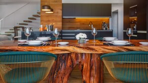 Een moderne eetruimte met een houten tafel, groene stoelen en een keuken op de achtergrond.