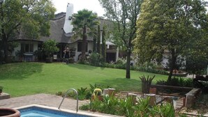 Una piscina amb vora de rajola, envoltada per un jardí ben cuidat i diferents plantes.