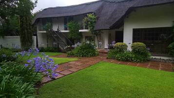 A traditional building with a thatched roof, a well-maintained lawn, and a variety of flowering plants.