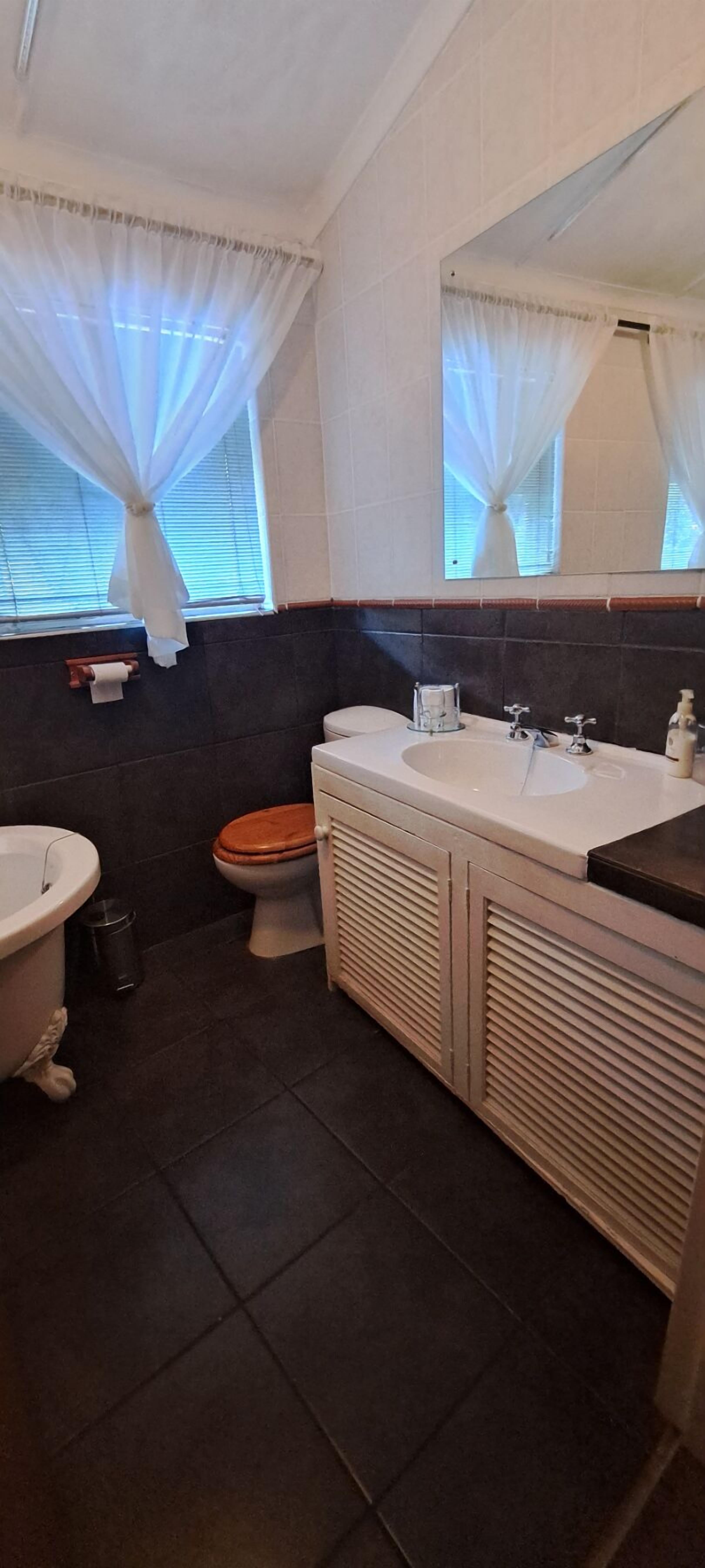 A bathroom with a bathtub, toilet, and sink area.