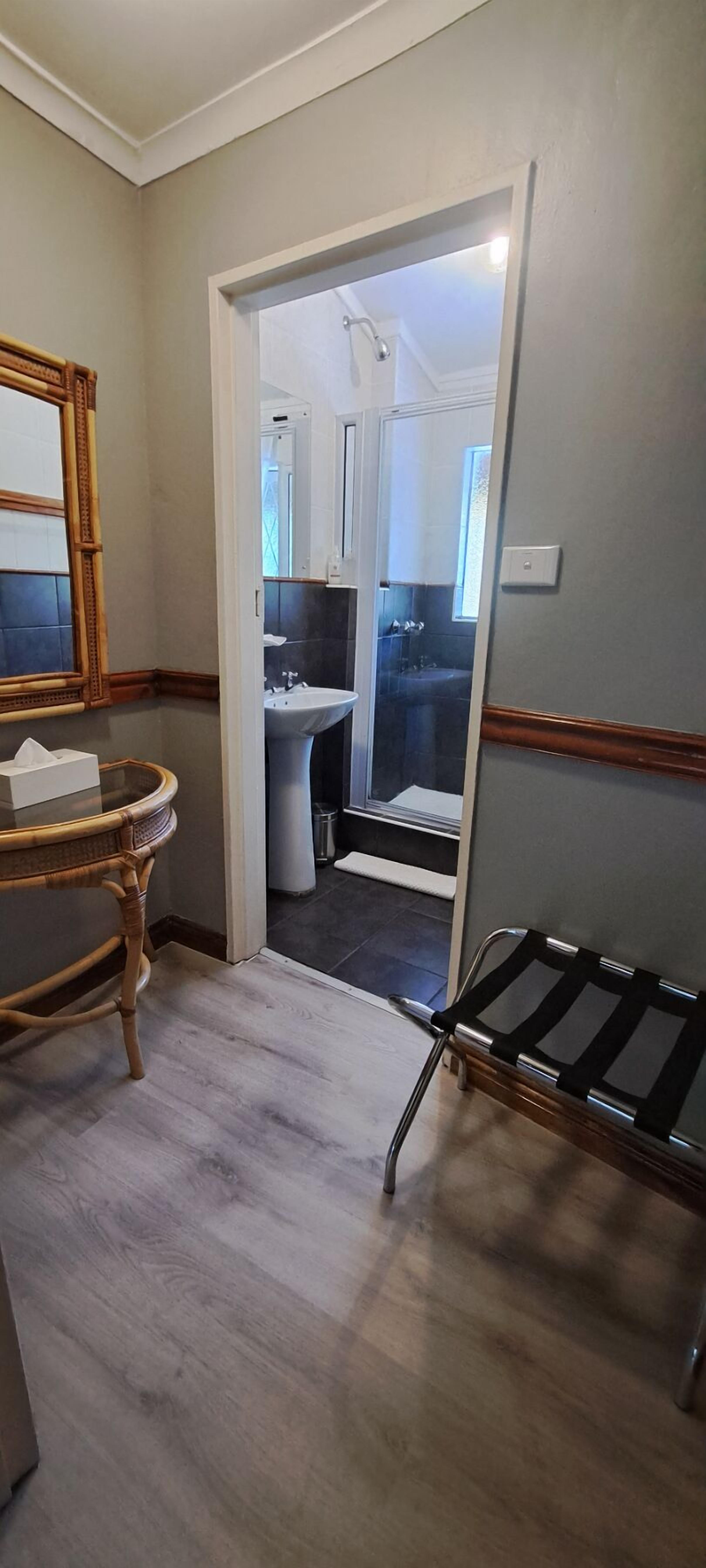 A bathroom with a white sink, a mirror, and a wooden chair.