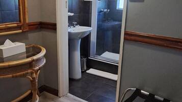 A bathroom with a white sink, a mirror, and a wooden chair.