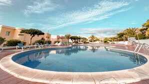 En swimmingpool med solstolar och en klar himmel.