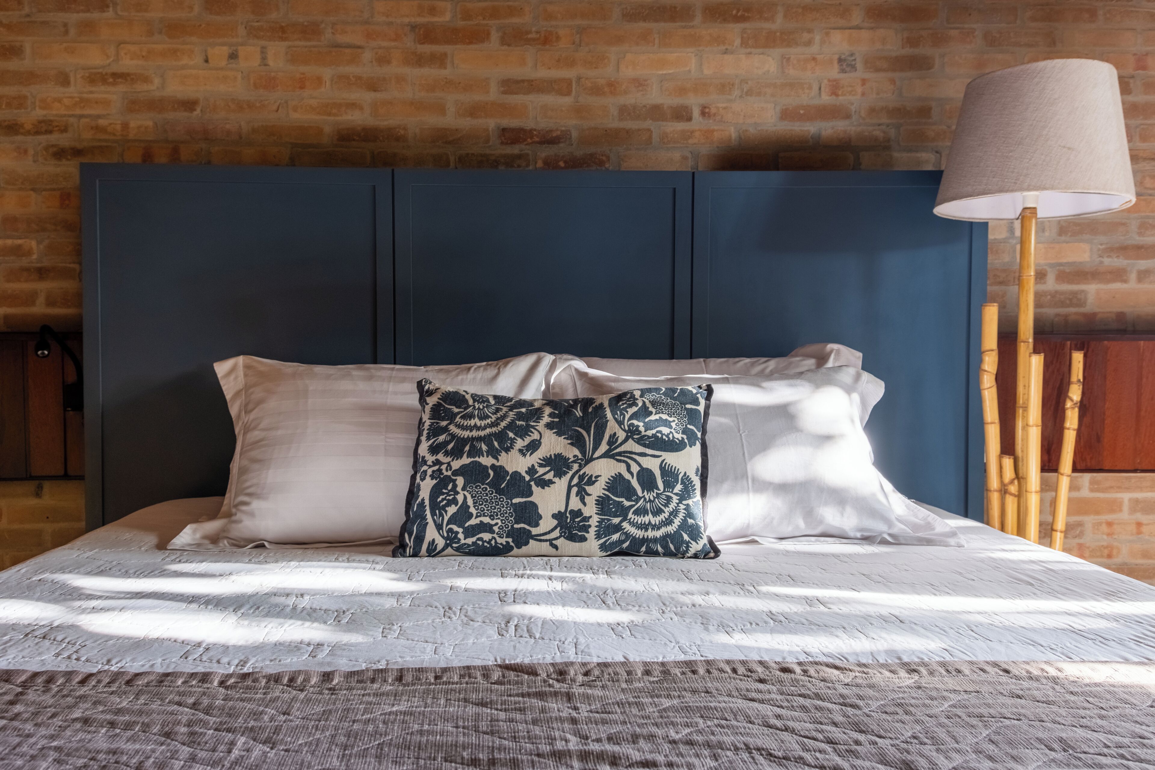 A bed with a blue headboard, white pillows, and a patterned throw.