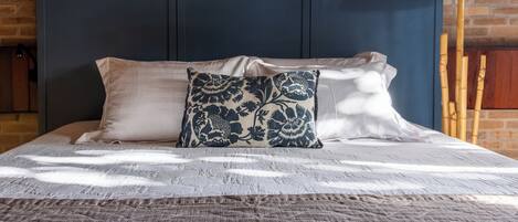 A bed with a blue headboard, white pillows, and a patterned throw.